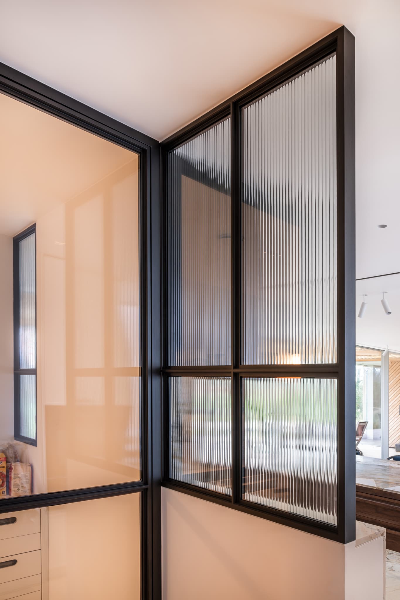 steel glazed fixed screen in black with fluted textured glass in a kitchen
