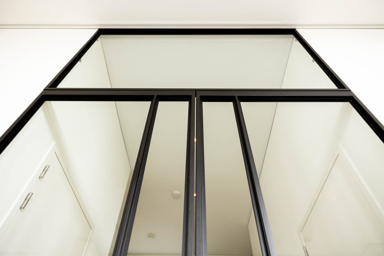 double interior doors in black steel and clear glass with a matching fixed panel above