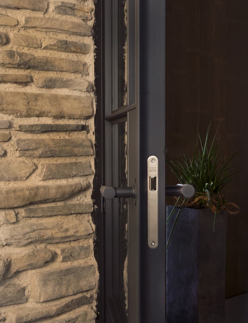 a black steel door inside a home with exposed brick