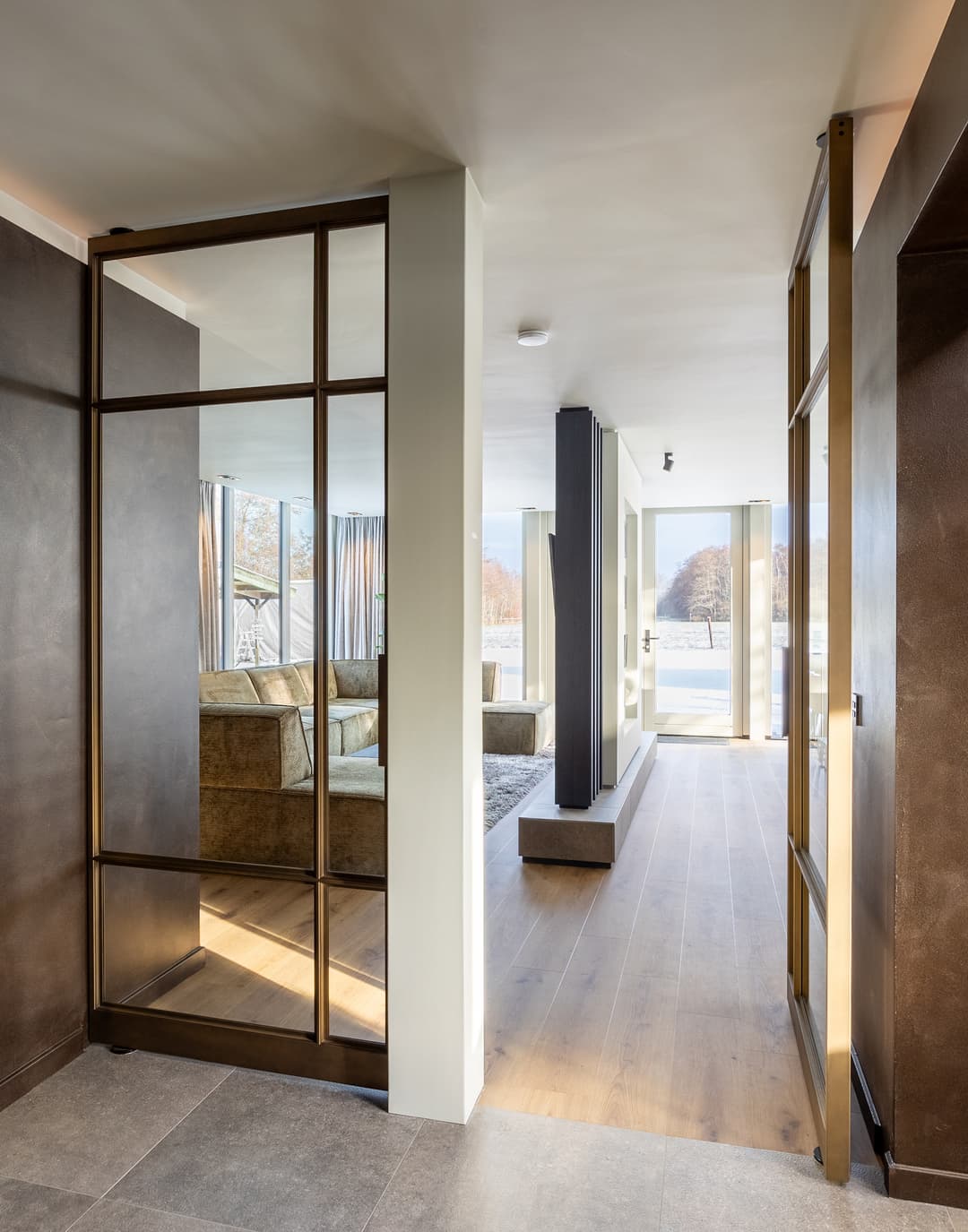 double pivoting steel-glazed doors in a bronze finish looking into a modern and warm toned living room